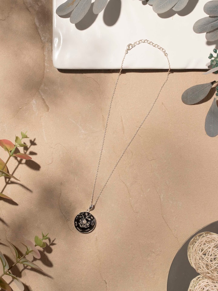 Close-up view of ceramic pendant and chain emphasizing intricate design and texture