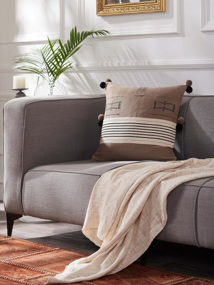 Sofa setup featuring khaki Naga cushion cover with tribal-inspired handloom design.