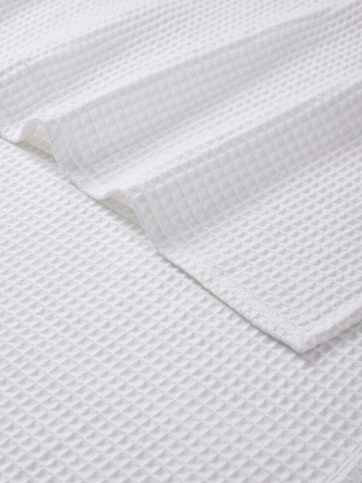 Angled view of Amala waffle white solid cotton bath towel displaying its edge and texture