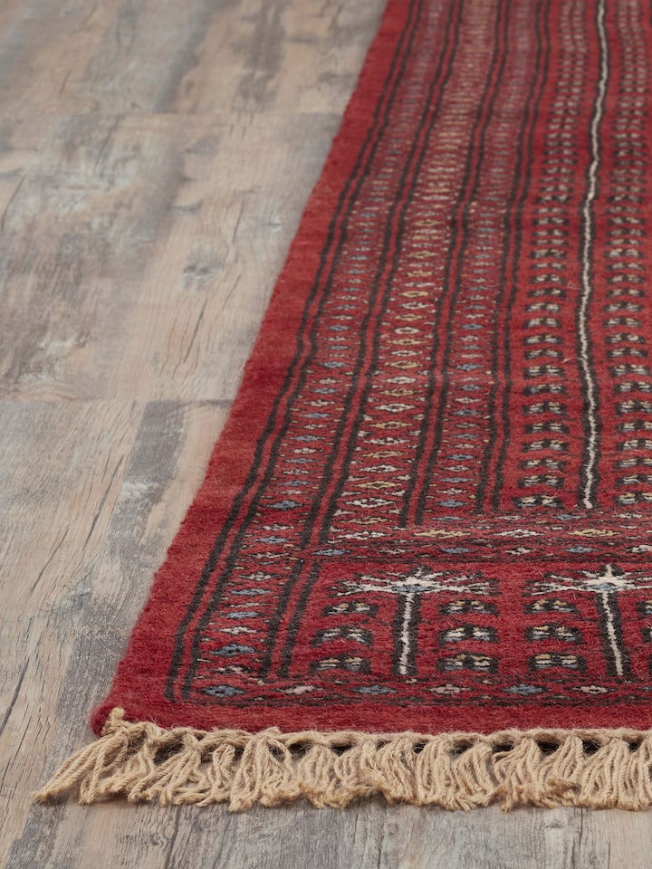 Overhead view of Amritsari Parda red Gwalior wool rug showing the full design and color variations