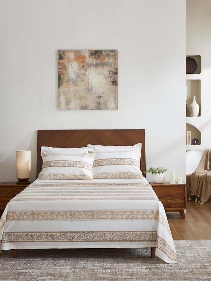Lifestyle image of a brown floral cotton Sanganeri block printed king bedsheet, displayed in a well-decorated bedroom.