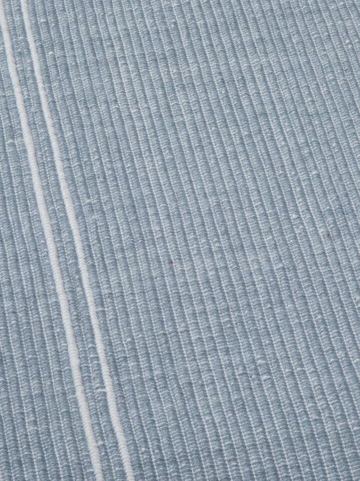 Detail shot 2: Detailed view of hemmed edge and striped fabric in soft light blue hues.