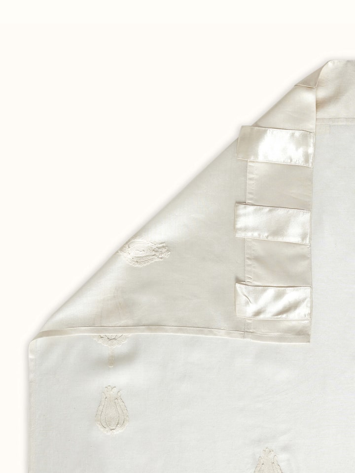 Back view of ivory curtain revealing neat reverse of hand embroidery and sheer drape.