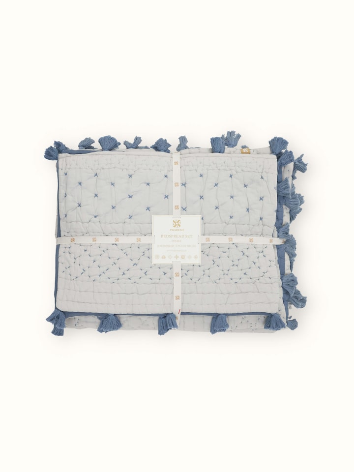Nitya Blue Textured Stripe Cotton Razai Embroidered Double Bedspread Set displayed on a bed, featuring its striped pattern.
