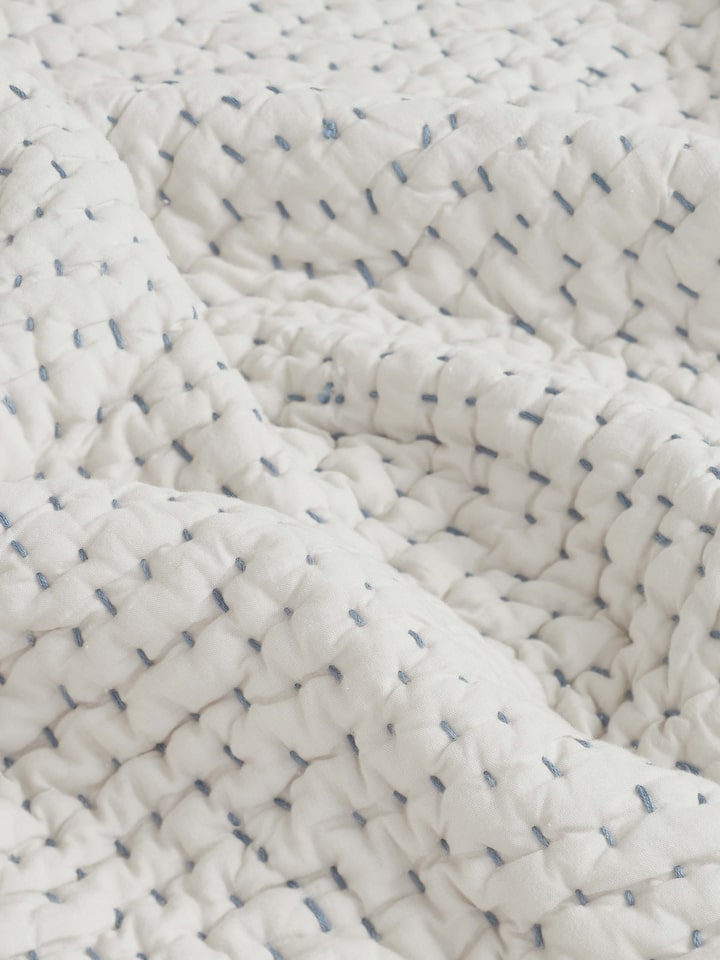 Detailed image of the edges and embroidery on the beige double bedspread, emphasizing the craftsmanship.