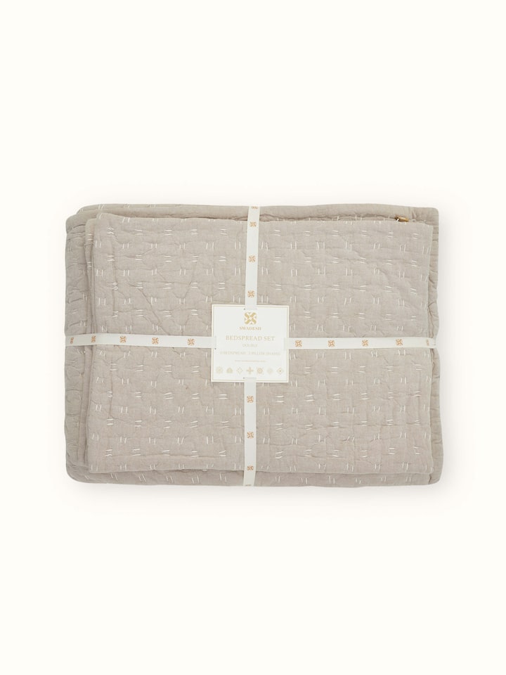 Lifestyle shot of Vaayu beige chambray textured cotton razai embroidered double bedspread set in a bed setting