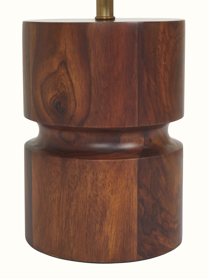 Angled view of tall beige wood and cotton fabric table lamp, emphasizing the lamp's stylish appearance and soft glow.
