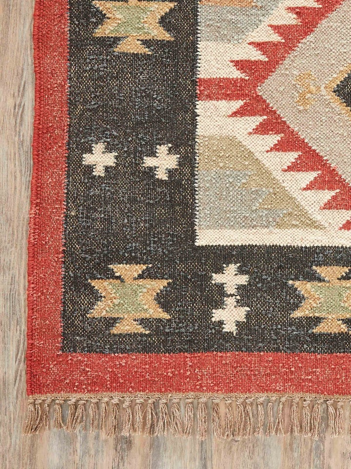 Traditional Kilim Black Lawan jute & wool panja dhurrie displayed on the floor, showing its full design and use in a room setting.