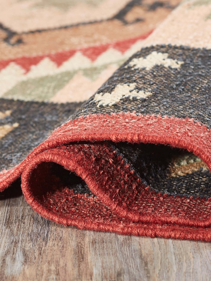 Traditional Kilim Black Lawan jute & wool panja dhurrie folded, showcasing the texture and pattern details.