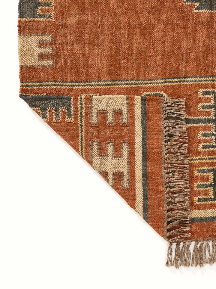 Angled view of Traditional Kilim rust lawan wool & jute panja dhurrie highlighting the color depth and design elements