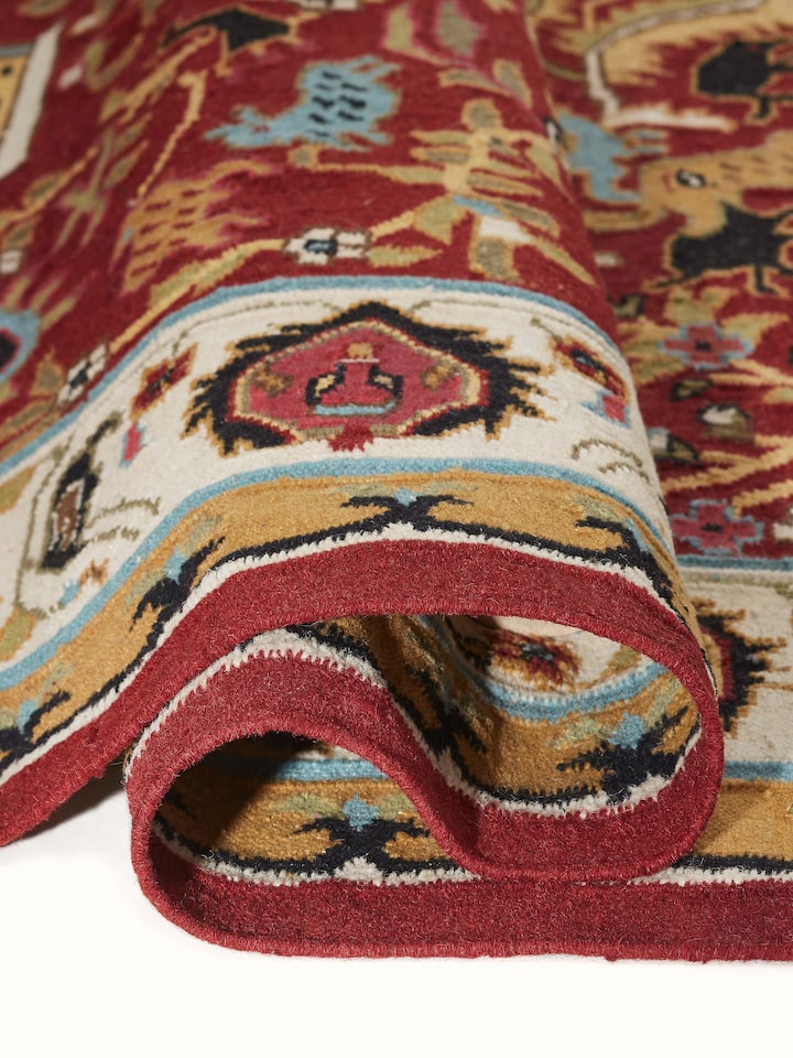 Folded Village pictorial red wool & cotton panja dhurrie, showing the thickness and texture of the fabric