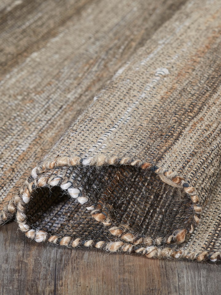 Textured Beige Charcoal Lawan Jute & Cotton Natural Fibre Rug displayed in a room setting, highlighting its versatile use.