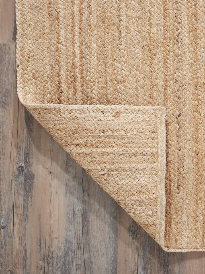 Full view of the braided stripe beige Lawan jute natural fibre rug, showcasing its placement and design in a room setting.