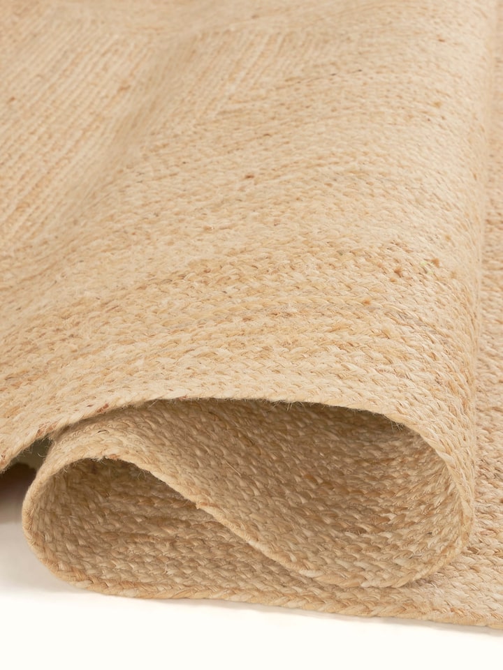 Side view of Braided Concentric Rectangle Beige Lawan Jute Natural Fibre Rug (5x8 ft) showcasing the thickness and edge detailing.