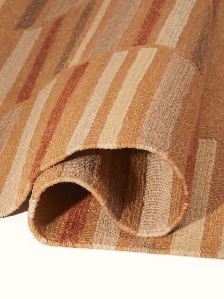 Perspective view of Geo solid textured sumak rust Bhadohi wool hand-knotted rug showing the overall design and color richness.