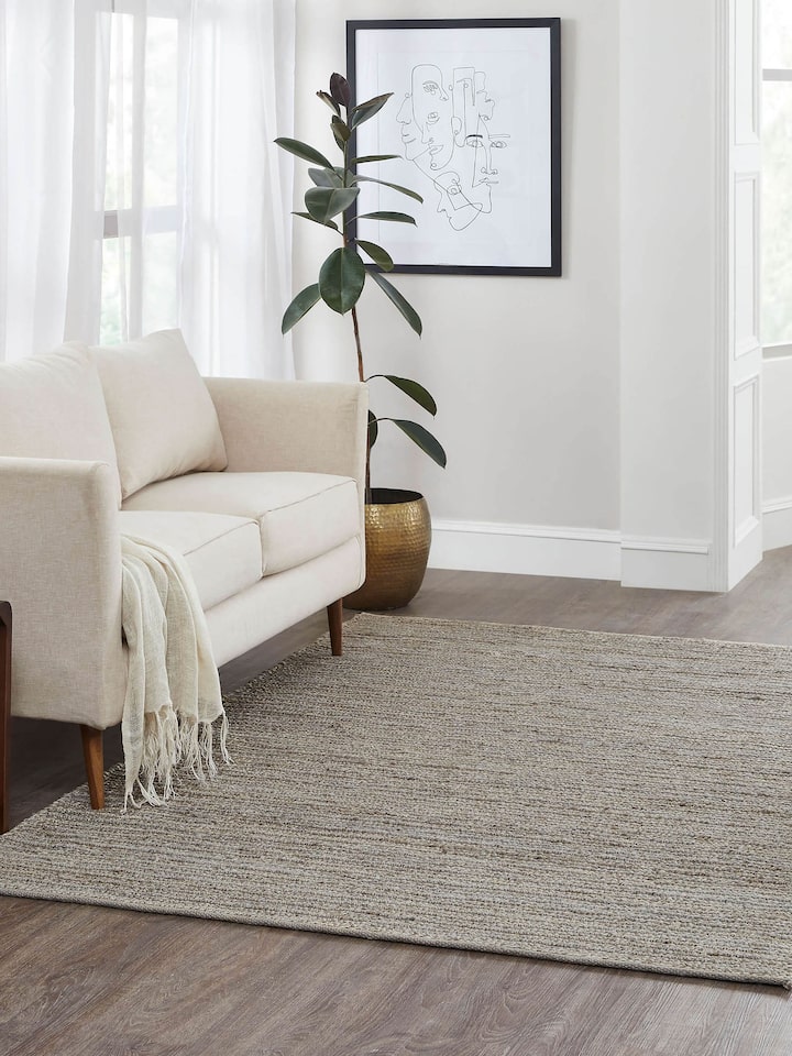 Living room view of large grey jute rug with natural fiber texture and solid minimalist design.