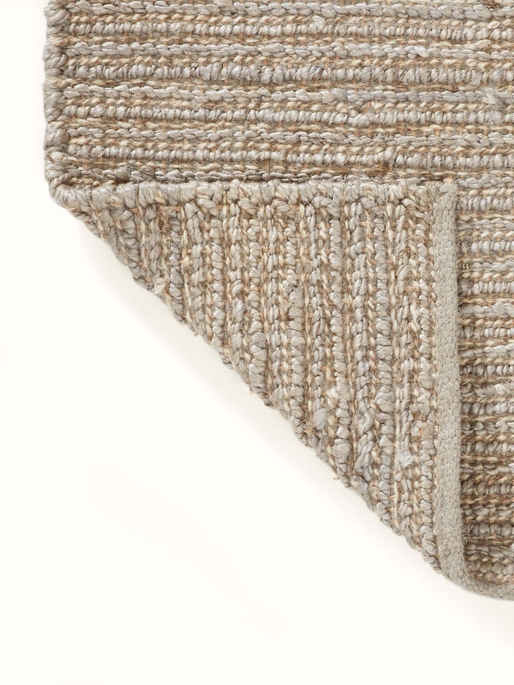 Textured Solid Grey Jute & Wool Rug (5x8 ft) placed on a floor, illustrating its use in a home setting.
