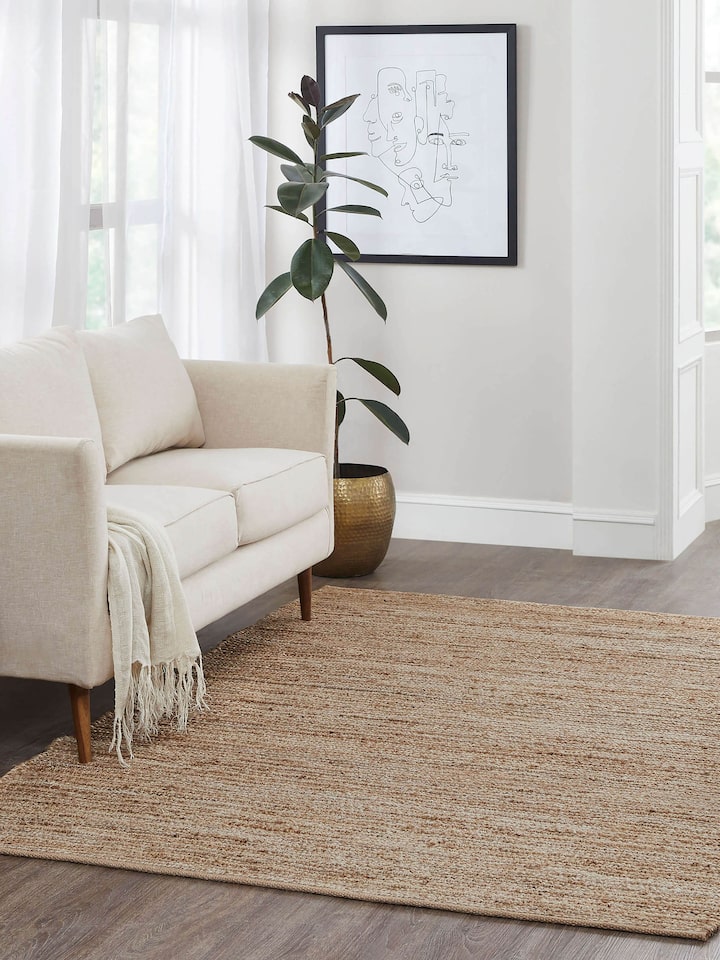 Living room styled with solid beige jute rug in natural fibre, measuring 5x8 ft.