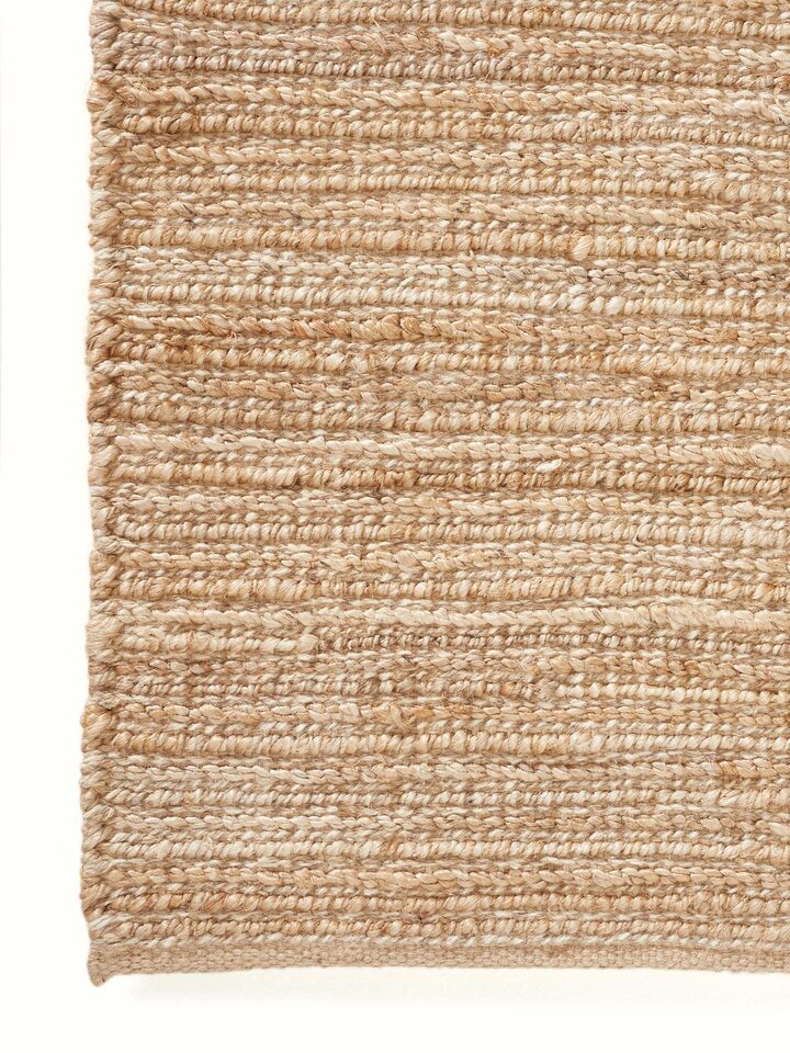 Detailed view of textured solid beige jute & wool natural fibre rug (5x8 ft) emphasizing the rug's texture and quality.