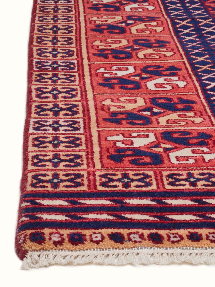 Angled view of Kazak tribal red Agra wool hand-knotted rug (6x9 ft), displaying the rug’s design and color depth.