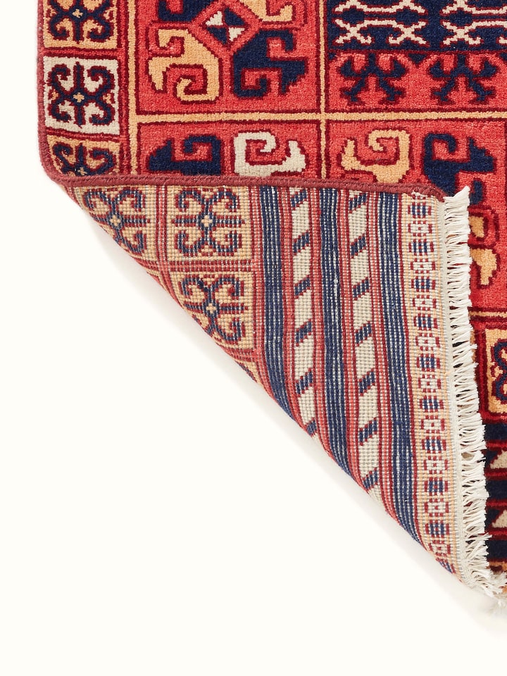 Side view of Kazak tribal red Agra wool hand-knotted rug (6x9 ft), demonstrating its thickness and texture.