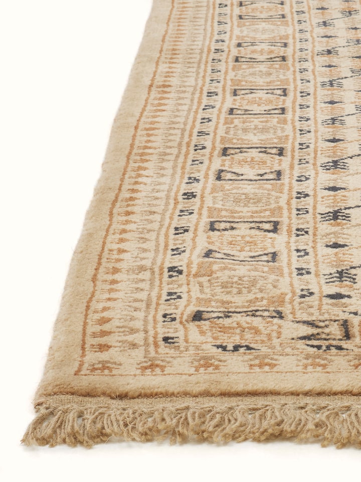 Traditional Bukhara beige rust Gwalior wool hand-knotted rug displayed in a room setting, illustrating its size and overall appearance