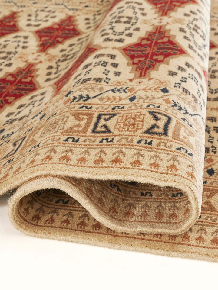 Close-up of Traditional Bukhara beige rust Gwalior wool hand-knotted rug's texture, emphasizing the wool fibers and pattern details