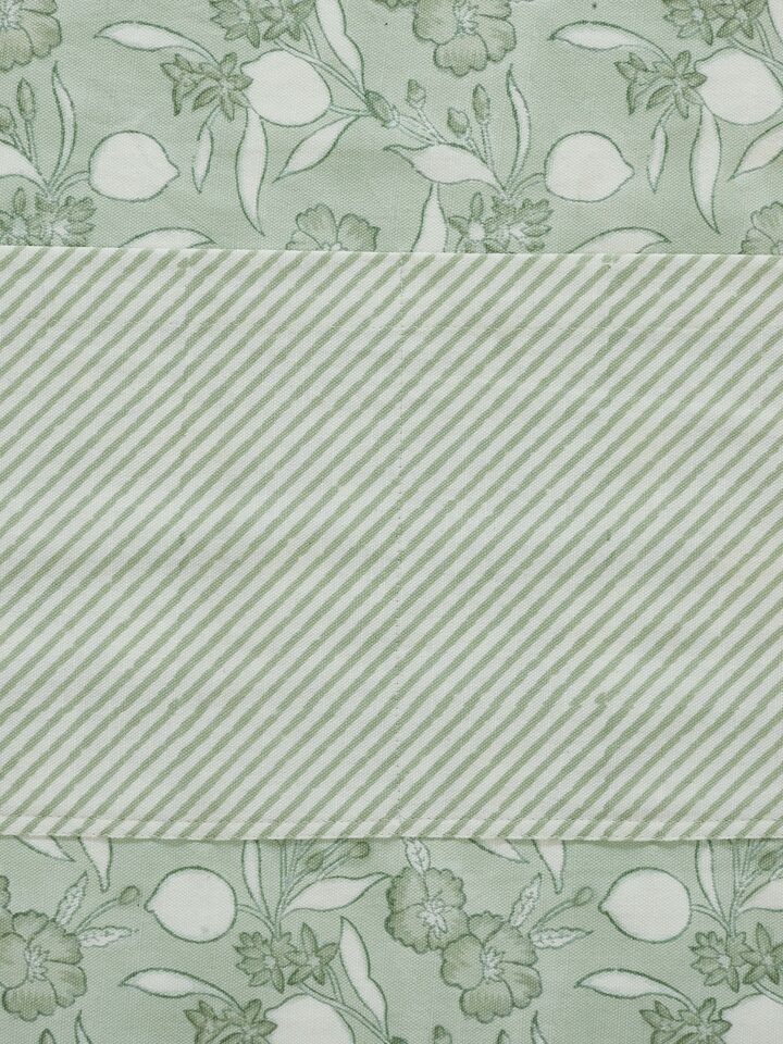 Green floral cotton Sanganeri block printed apron displayed with emphasis on its print and overall design.
