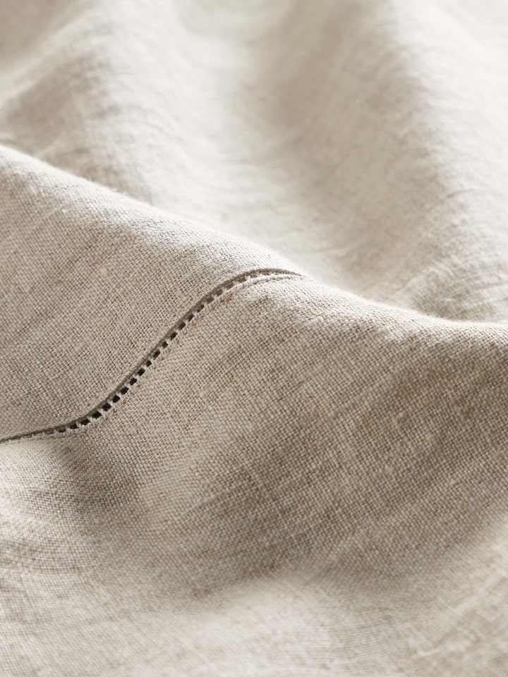 Angled view of Mughal Beige Floral Linen Kashmir Chain Stitch Embroidered Table Cover on a dining table, highlighting the elegant design.