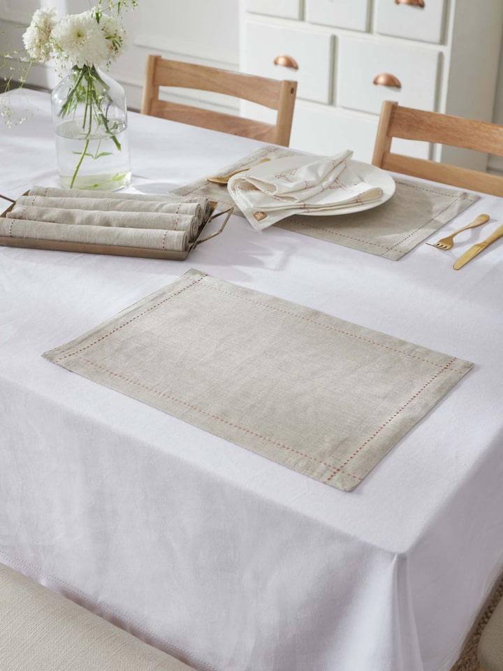 Table setting view with beige hand-embroidered linen mats enhancing classic dining decor.
