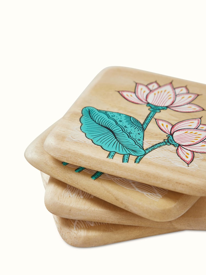 Detailed view of the carved gamhar wood coasters in white and teal, highlighting their craftsmanship and design.