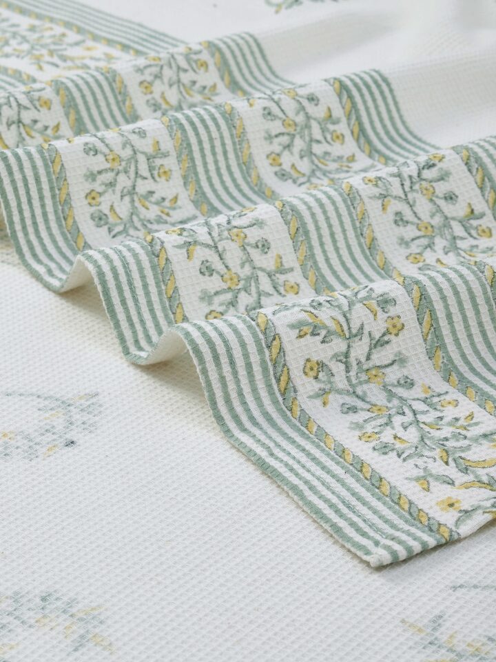 Perspective view of Ambi allover yellow floral cotton Sanganeri block printed bath towel (L) displaying its full print and size.
