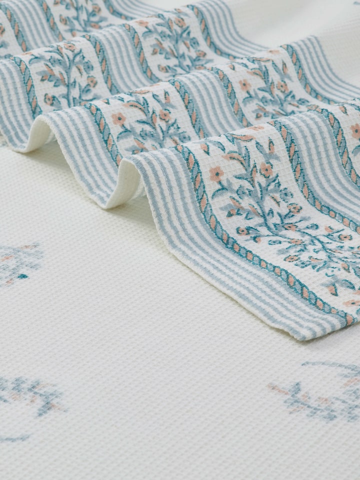 Detailed view of Ambi allover blue floral cotton Sanganeri block printed bath towel (L) highlighting the block print and fabric texture.
