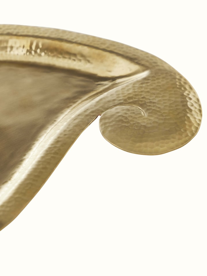 Close-up view of Polished brass paisley pooja thali focusing on the intricate brasswork and refined texture.