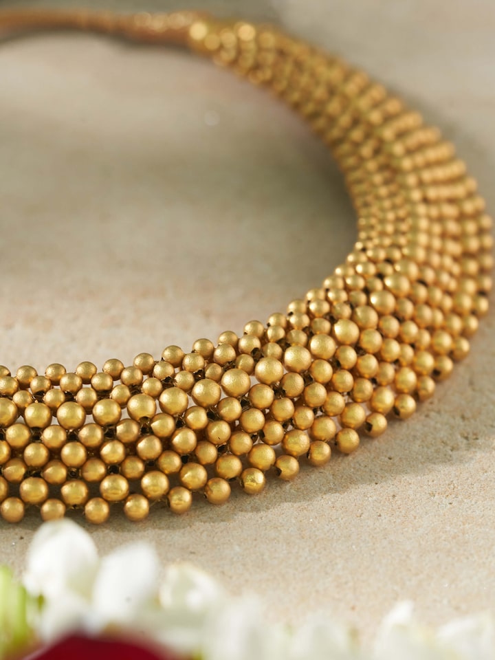 Close-up detail shot showing intricate gold beadwork and tightly knotted gold thread
