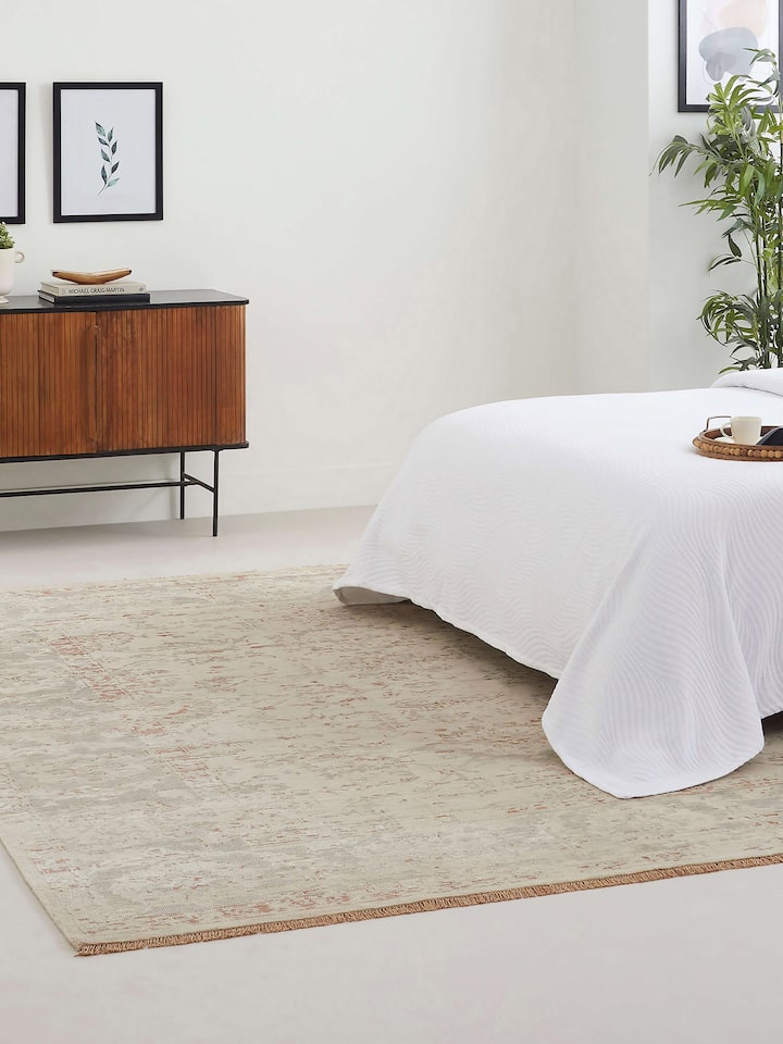 Room view of hand-knotted beige and grey Bhadohi rug with distressed transitional pattern in wool and silk blend.