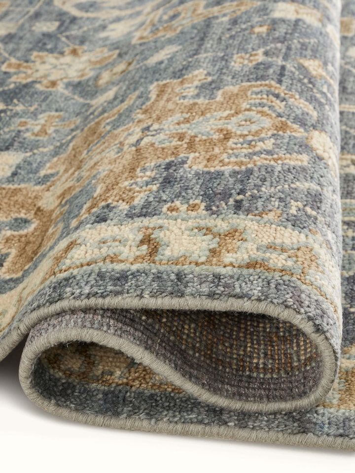 Angled view of Oushak traditional blue Bhadohi wool hand-knotted rug kharad showing the full pattern and edge detailing.