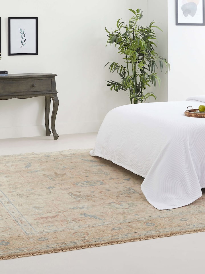 Beige Oushak wool rug styled in a room, showing ornate Bhadohi hand-knotted motifs