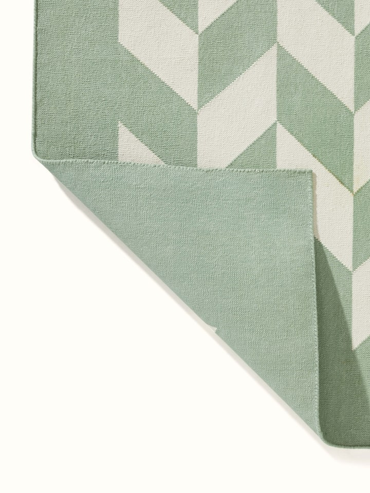 Modern geo chevron light green ivory lawan cotton panja dhurrie kharad featuring a close-up of the geometric design and fabric.