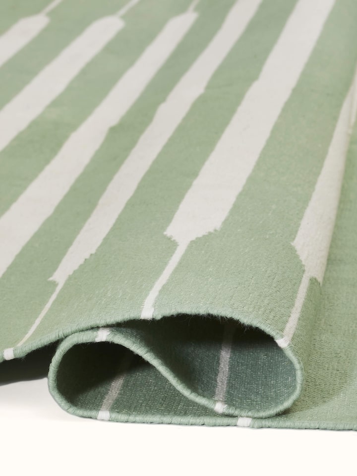 Modern geo stripe light green ivory lawan cotton panja dhurrie kharad in a room setting highlighting its use as a stylish floor covering.