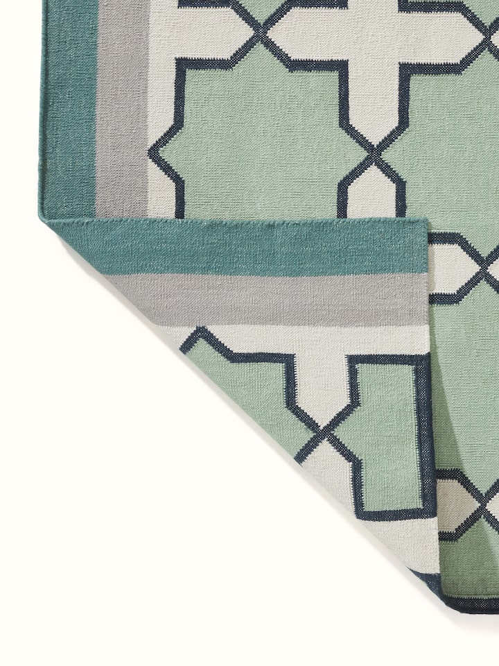 Full view of Modern Geo Jharokha green grey Lawan cotton Panja dhurrie laid out, demonstrating its size and overall design in a room setting