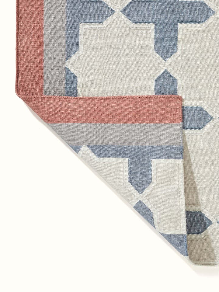 Modern geo jharokha grey blue lawan cotton panja dhurrie rolled up to show the design details and fabric.