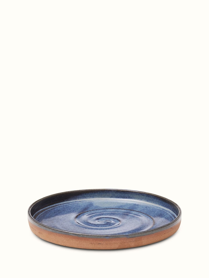 Side view of studio pottery ceramic blue dessert plate highlighting its curved edges and artisanal craftsmanship