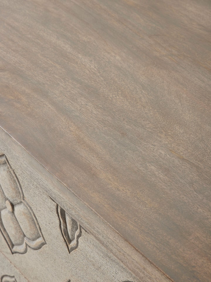 Close-up of the carved top of the mango wood chest of drawers, highlighting the craftsmanship and texture