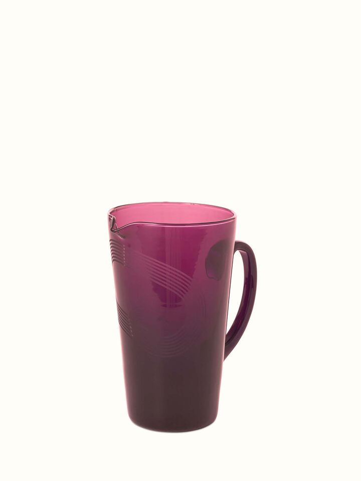 Angled view of Firozabadi glass pitcher in purple emphasizing its stylish spout and handle.