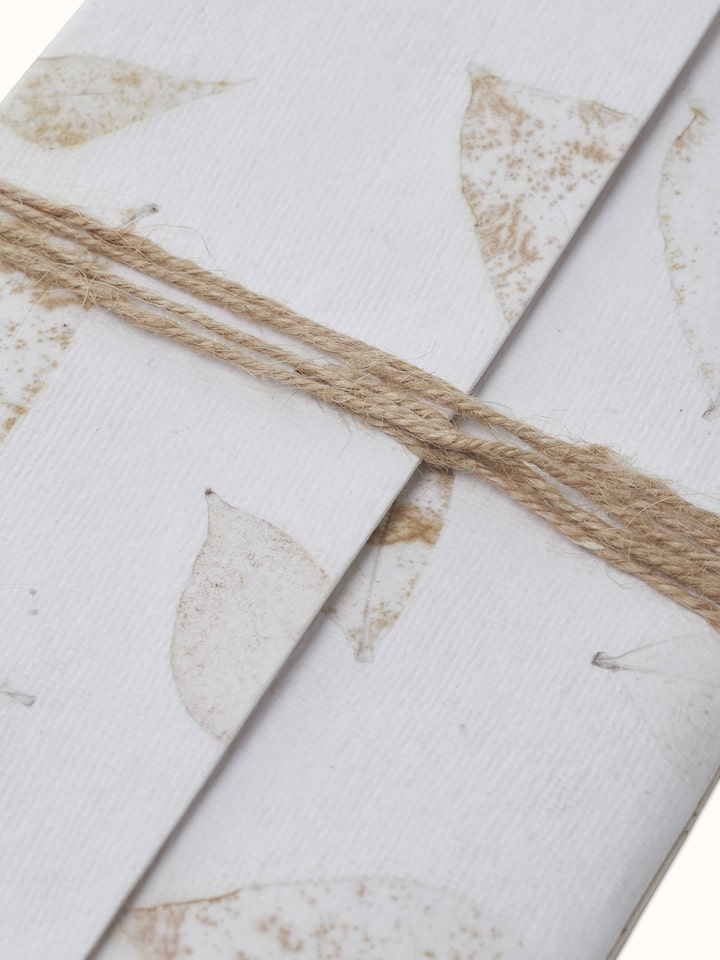 Angle view of Auroville Handmade Paper Notebook with Rope in white, showing the notebook's overall structure.