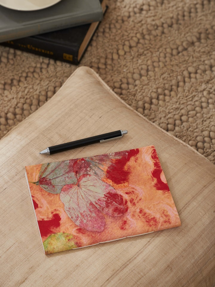 Side view of Auroville handmade paper notebook in orange showcasing its handcrafted binding and vibrant color.