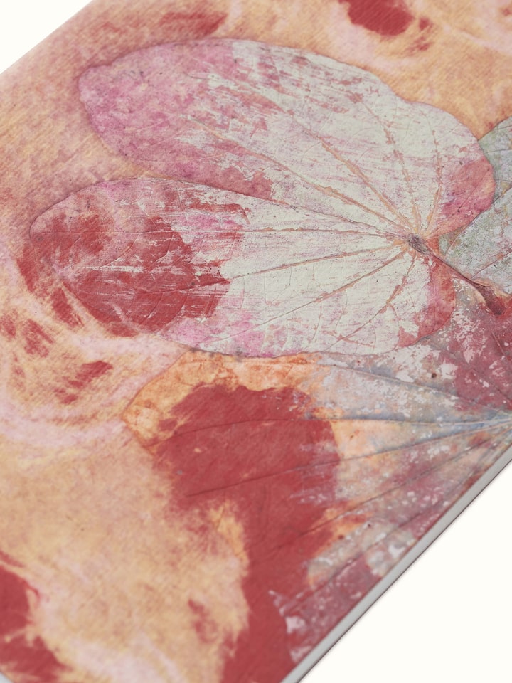 Angled view of Auroville handmade paper notebook in orange emphasizing its artisanal craftsmanship and page texture.