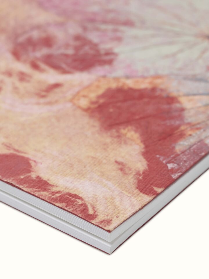 Close-up view of Auroville handmade paper notebook in orange focusing on the handmade paper quality and design details.