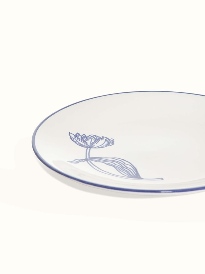 Close-up of white and blue Khurja pottery ceramic dinner plates, focusing on the intricate blue patterns and white ceramic base.